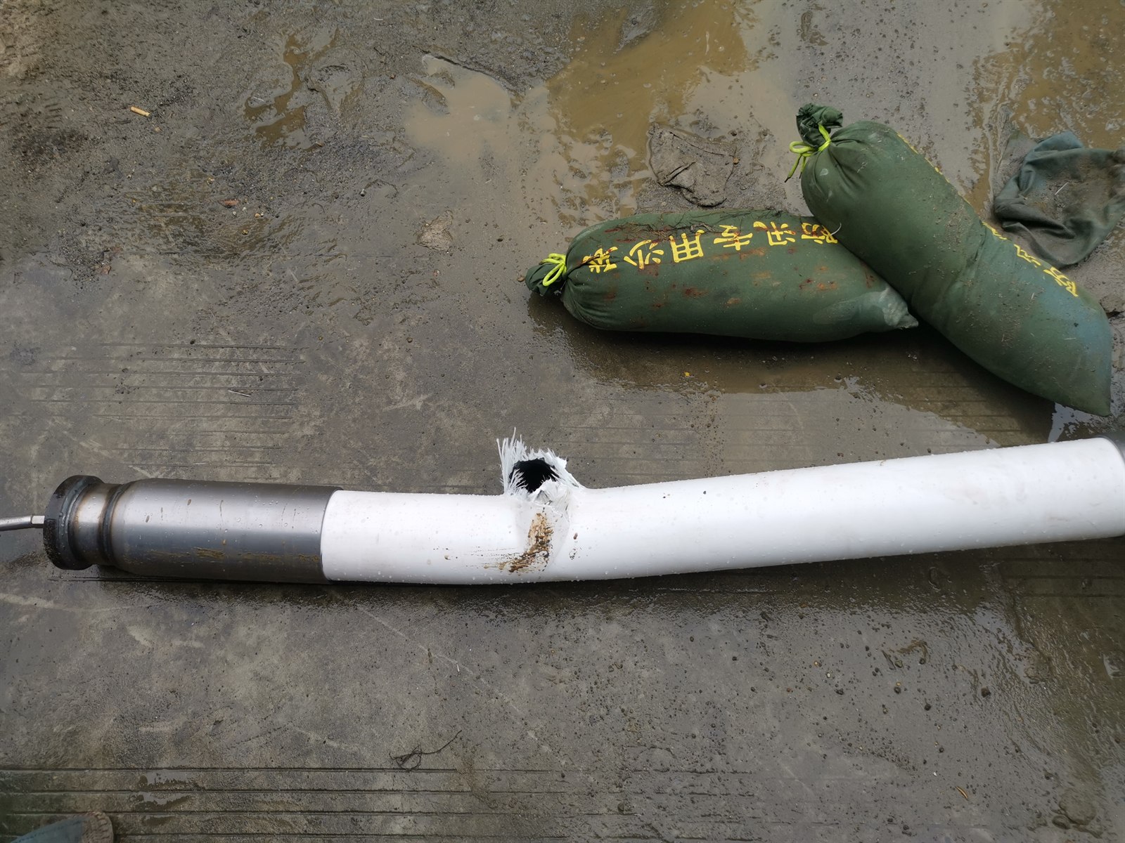 Post-burst RTP pipe specimen beside protective sandbags after pressure testing