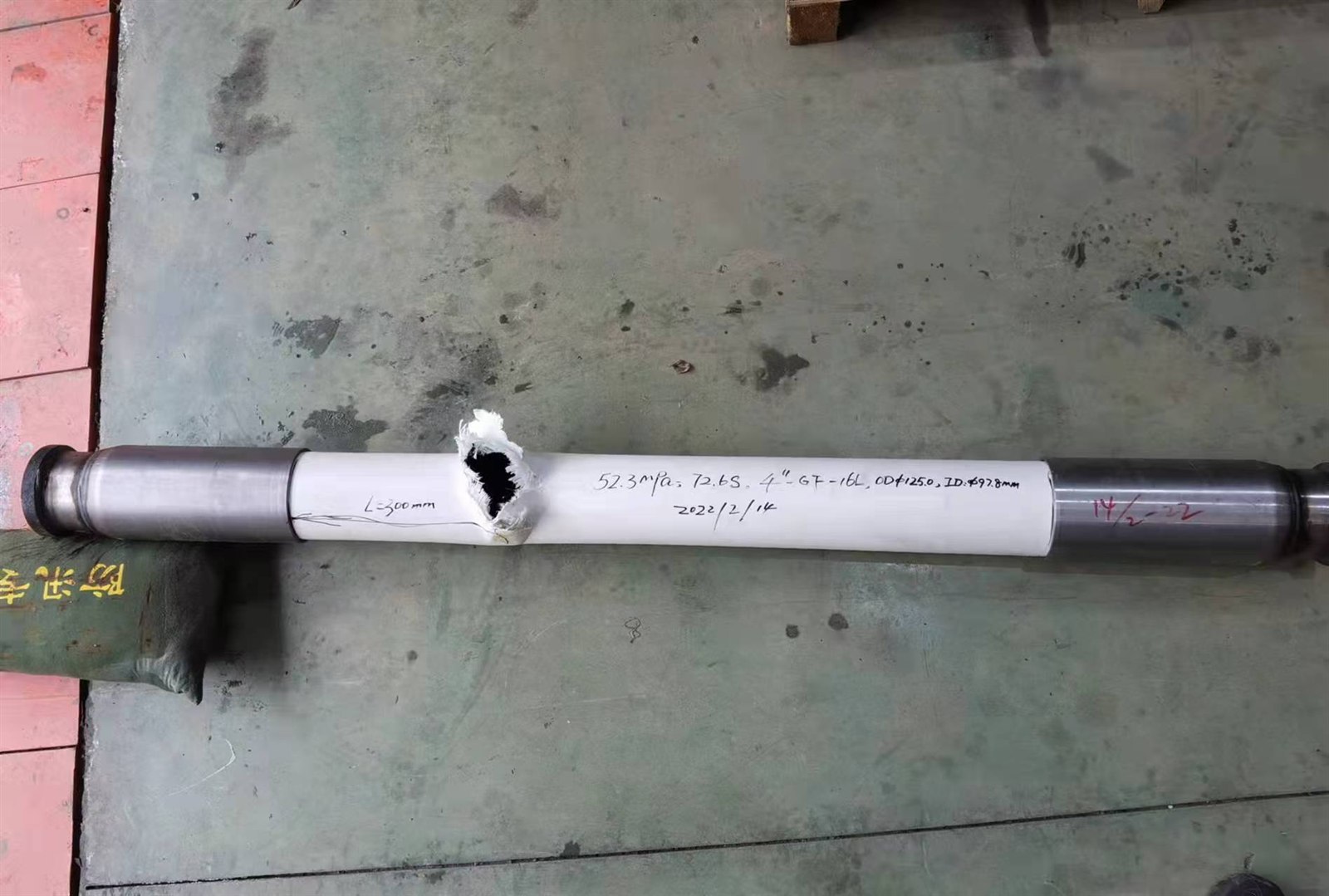 Single burst-tested RTP pipe specimen with test markings and exposed reinforcement