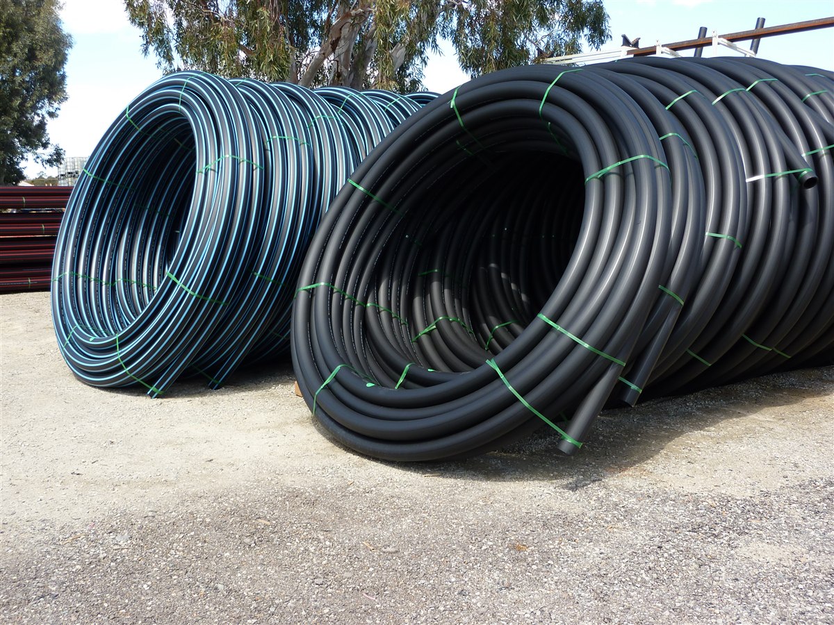 Coiled black polyethylene pipe stacked in coils after production